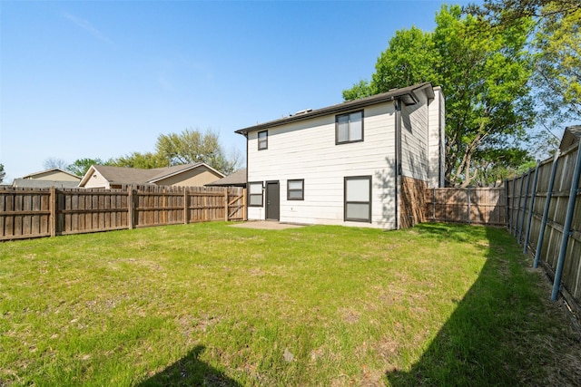 rear view of property featuring a fenced backyard and a yard
