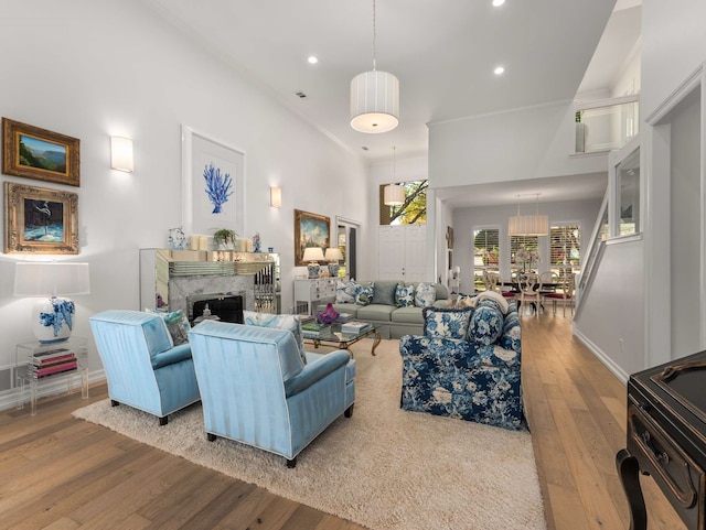 living area with a fireplace, hardwood / wood-style floors, recessed lighting, baseboards, and ornamental molding