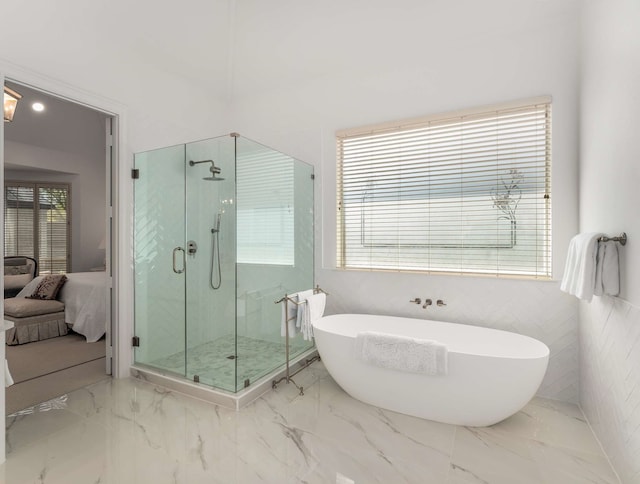 full bathroom with a stall shower, a soaking tub, marble finish floor, and ensuite bath