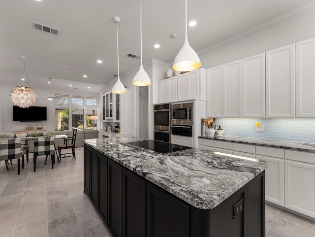kitchen featuring a center island, stainless steel appliances, decorative backsplash, visible vents, and ornamental molding