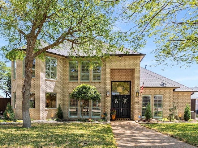 traditional-style home with brick siding and a front lawn