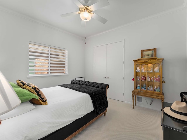 bedroom featuring light colored carpet, ornamental molding, ceiling fan, and a closet