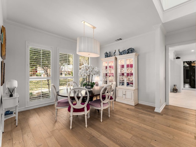 dining room featuring crown molding, baseboards, visible vents, and light wood-style floors