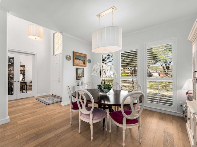 dining area featuring baseboards, ornamental molding, and light wood-style flooring