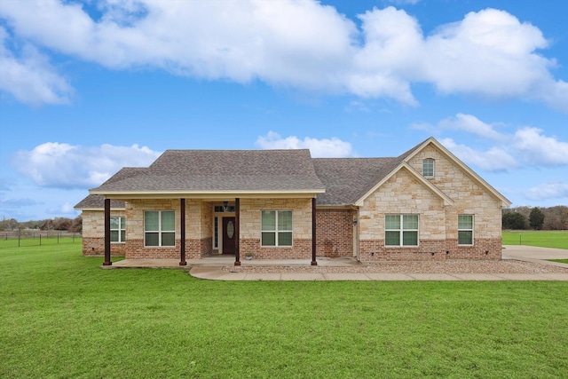 view of front of home with stone siding, brick siding, a front lawn, and roof with shingles