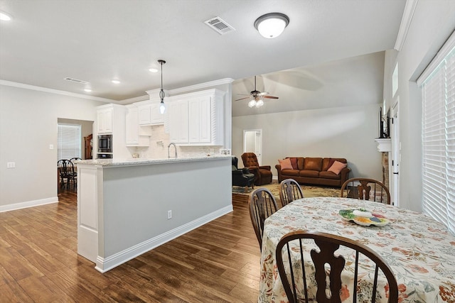dining room featuring a ceiling fan, baseboards, visible vents, ornamental molding, and dark wood-style flooring