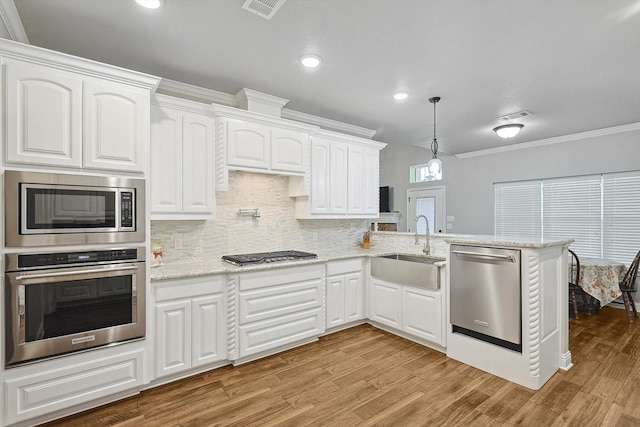 kitchen with a sink, light wood-style floors, visible vents, a peninsula, and appliances with stainless steel finishes