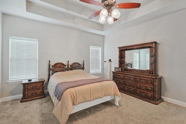 bedroom featuring a tray ceiling, carpet, and baseboards