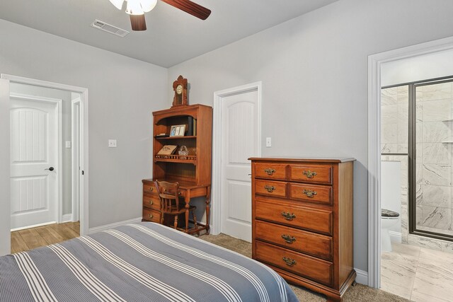 bedroom featuring baseboards, ensuite bath, ceiling fan, and visible vents