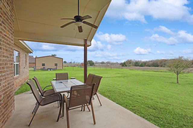 view of patio / terrace featuring a rural view, fence, outdoor dining space, and ceiling fan