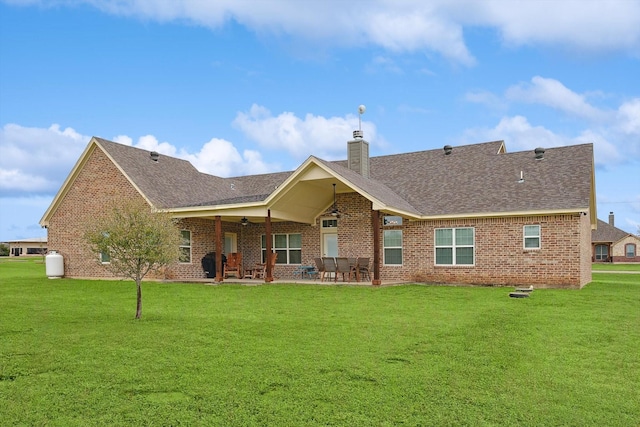 back of property featuring a patio, brick siding, and a lawn