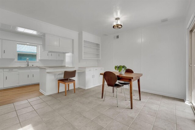 kitchen with light tile patterned floors, light countertops, a sink, white cabinetry, and visible vents