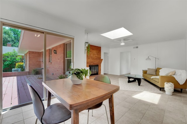dining area with a fireplace, light tile patterned flooring, visible vents, and a skylight