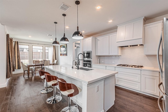 kitchen with light countertops, a sink, dark wood finished floors, stainless steel appliances, and visible vents