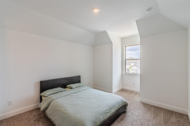 carpeted bedroom with baseboards and lofted ceiling