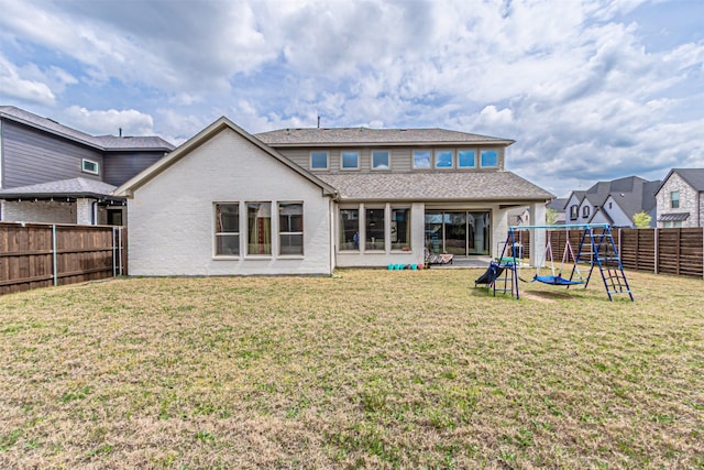 back of property featuring a lawn, brick siding, a fenced backyard, and a playground