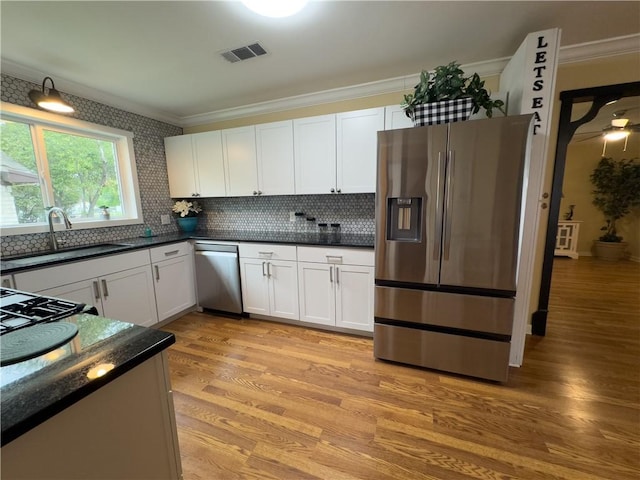 2717 Old Robinson Rd, Waco, TX 76706 - kitchen with stainless steel appliances, crown molding, a sink, light wood finished floors, and tasteful backsplash