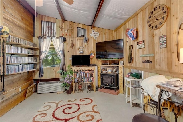 living area featuring wood walls, lofted ceiling with beams, and a wood stove