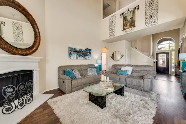 living room featuring visible vents, a high ceiling, arched walkways, and wood-type flooring