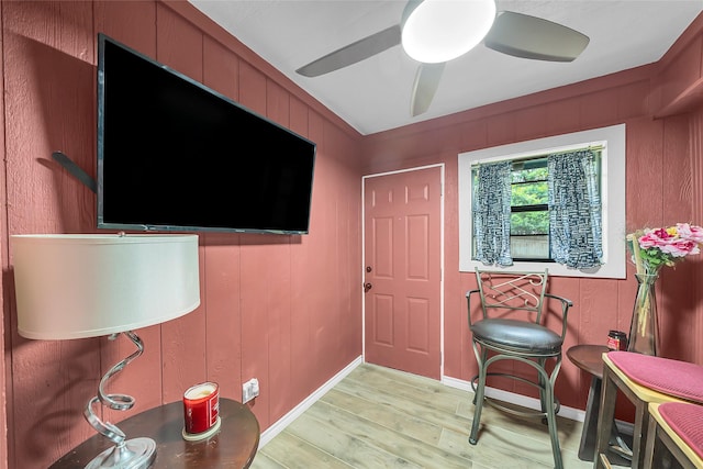 entryway with baseboards, ceiling fan, light wood-style flooring, and wood walls