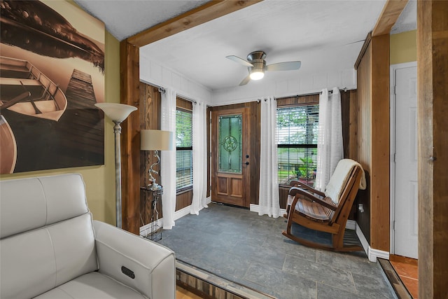 sitting room featuring baseboards, ceiling fan, and wooden walls