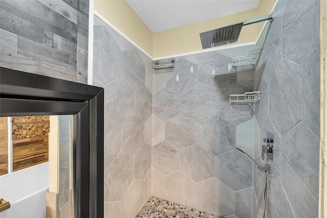 full bathroom featuring a tile shower and a textured ceiling