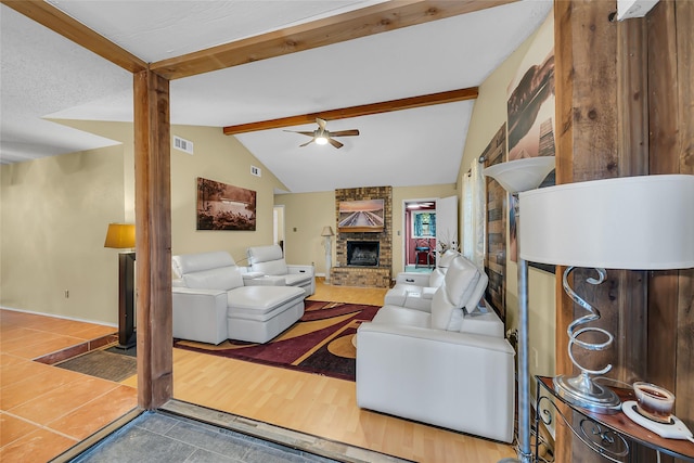 living area with ceiling fan, visible vents, vaulted ceiling with beams, a fireplace, and wood finished floors