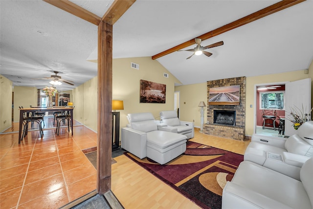 living room featuring lofted ceiling with beams, a fireplace, visible vents, and a ceiling fan