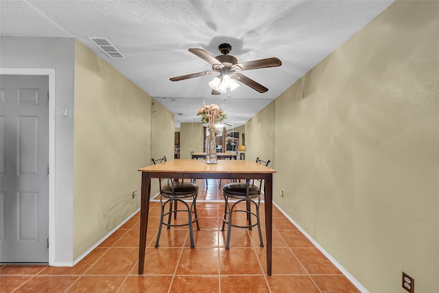 dining area with tile patterned floors, a textured ceiling, ceiling fan, and visible vents