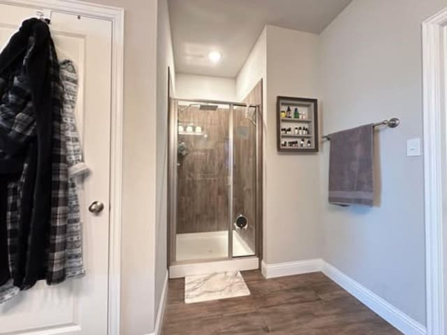 full bathroom with baseboards, wood finished floors, and a shower stall