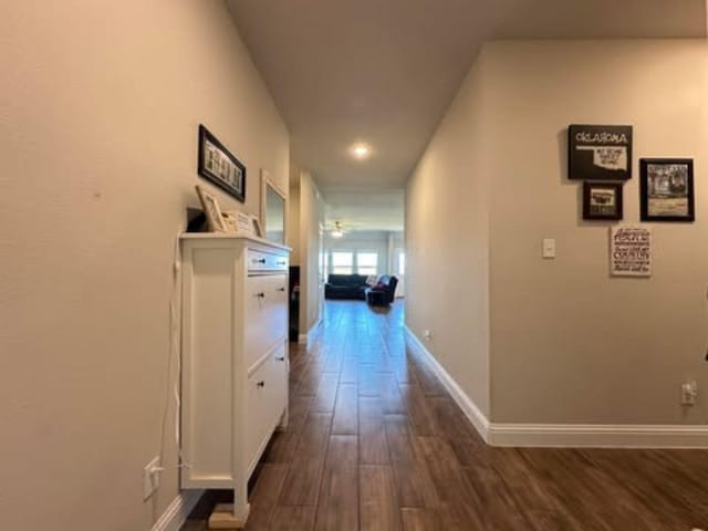 corridor featuring dark wood-style floors and baseboards