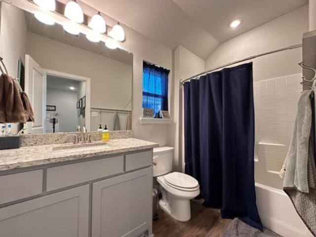 full bath featuring vanity, lofted ceiling, shower / tub combo with curtain, toilet, and wood finished floors