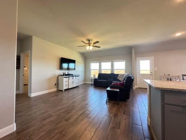 living area featuring dark wood-style floors, baseboards, and a ceiling fan