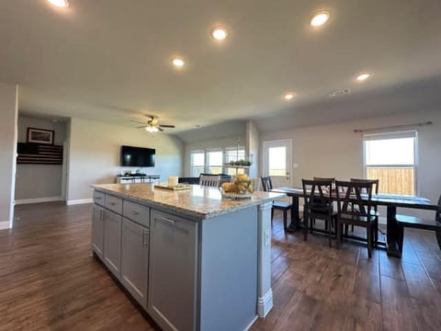 kitchen featuring dark wood-style flooring, a wealth of natural light, a center island, and a ceiling fan