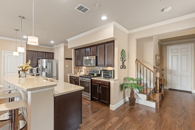 kitchen featuring visible vents, a breakfast bar area, appliances with stainless steel finishes, and dark brown cabinets