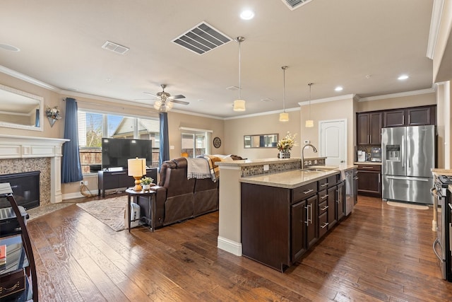 kitchen featuring open floor plan, stainless steel appliances, dark wood-type flooring, a sink, and dark brown cabinets