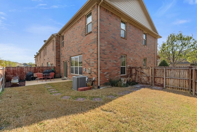 back of property featuring a lawn, brick siding, central AC, and a patio area