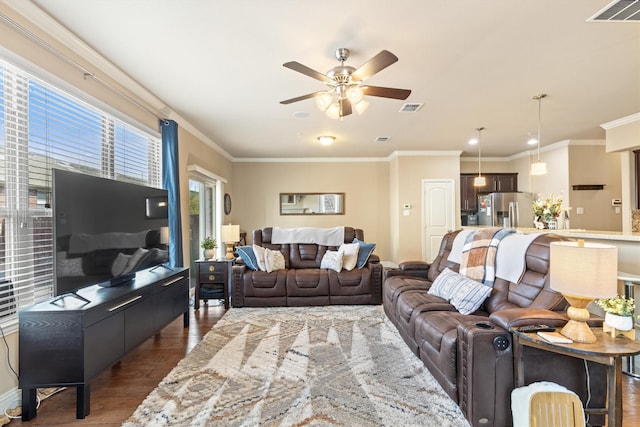 living room featuring dark wood-style flooring, ceiling fan, visible vents, and ornamental molding