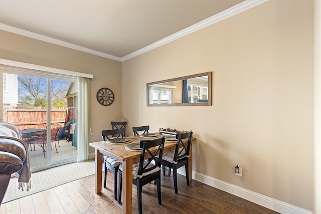 dining space featuring baseboards, crown molding, and wood finished floors