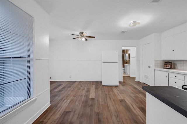 1326 W Shepherd St, Denison, TX 75020 - kitchen featuring freestanding refrigerator, white cabinets, dark wood finished floors, a ceiling fan, and tasteful backsplash