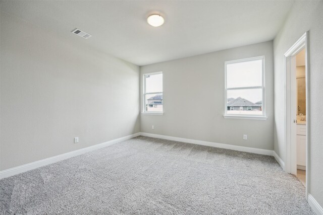 carpeted empty room featuring baseboards and visible vents
