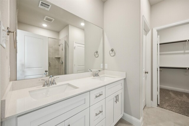 full bath featuring a sink, a walk in closet, a shower stall, and double vanity