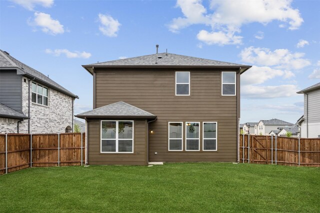 rear view of property with a lawn, a fenced backyard, and roof with shingles