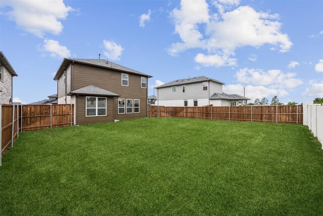back of house with a lawn and a fenced backyard