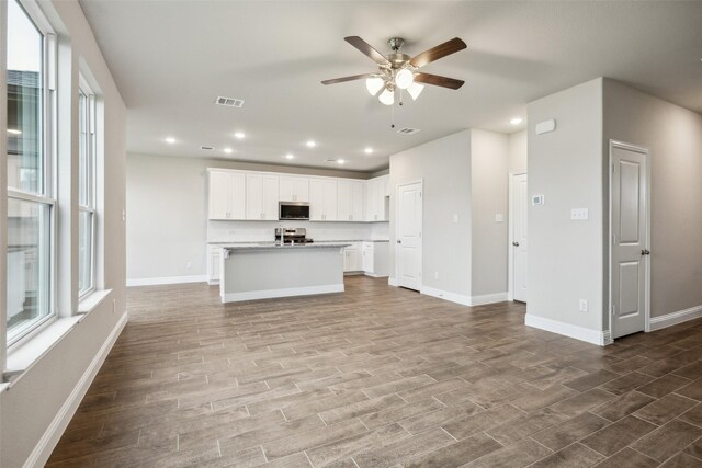 kitchen with visible vents, baseboards, open floor plan, ceiling fan, and stainless steel appliances