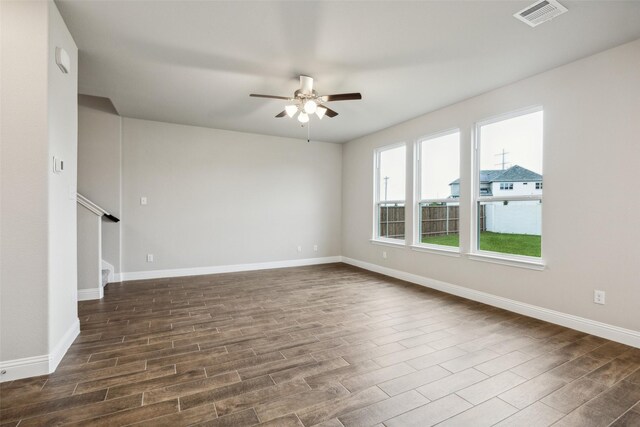 empty room with baseboards, ceiling fan, dark wood-style flooring, and visible vents