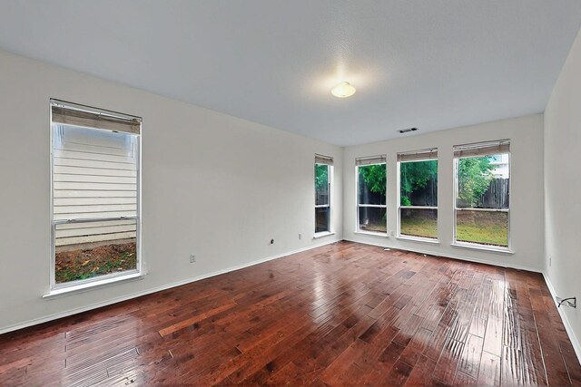 unfurnished room with baseboards, hardwood / wood-style floors, and visible vents