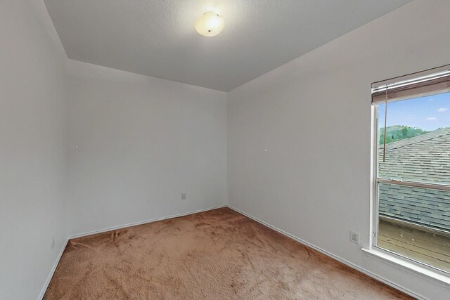 unfurnished room featuring baseboards and light carpet