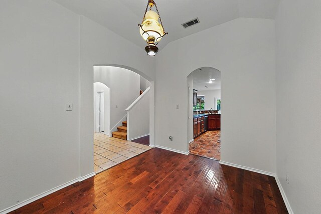 spare room with baseboards, lofted ceiling, and hardwood / wood-style flooring