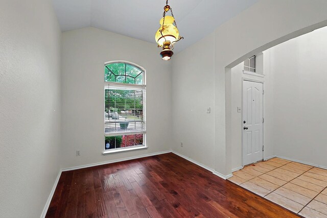 spare room with baseboards, lofted ceiling, and hardwood / wood-style flooring